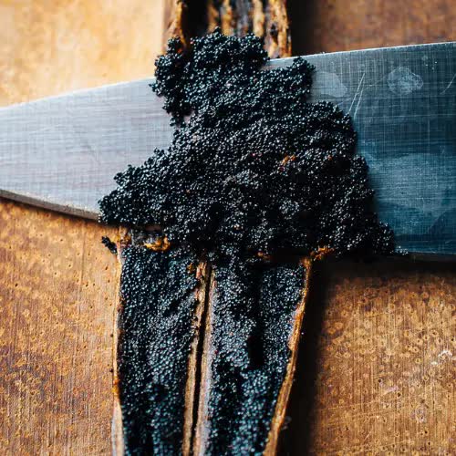 vanilla pods opened and a knife scraping out the vanilla seeds